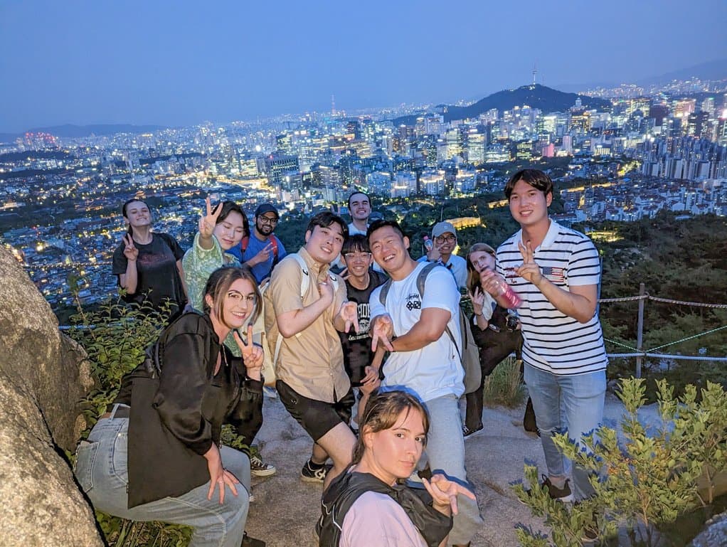 KB Kim hiking with community members overlooking Seoul at night